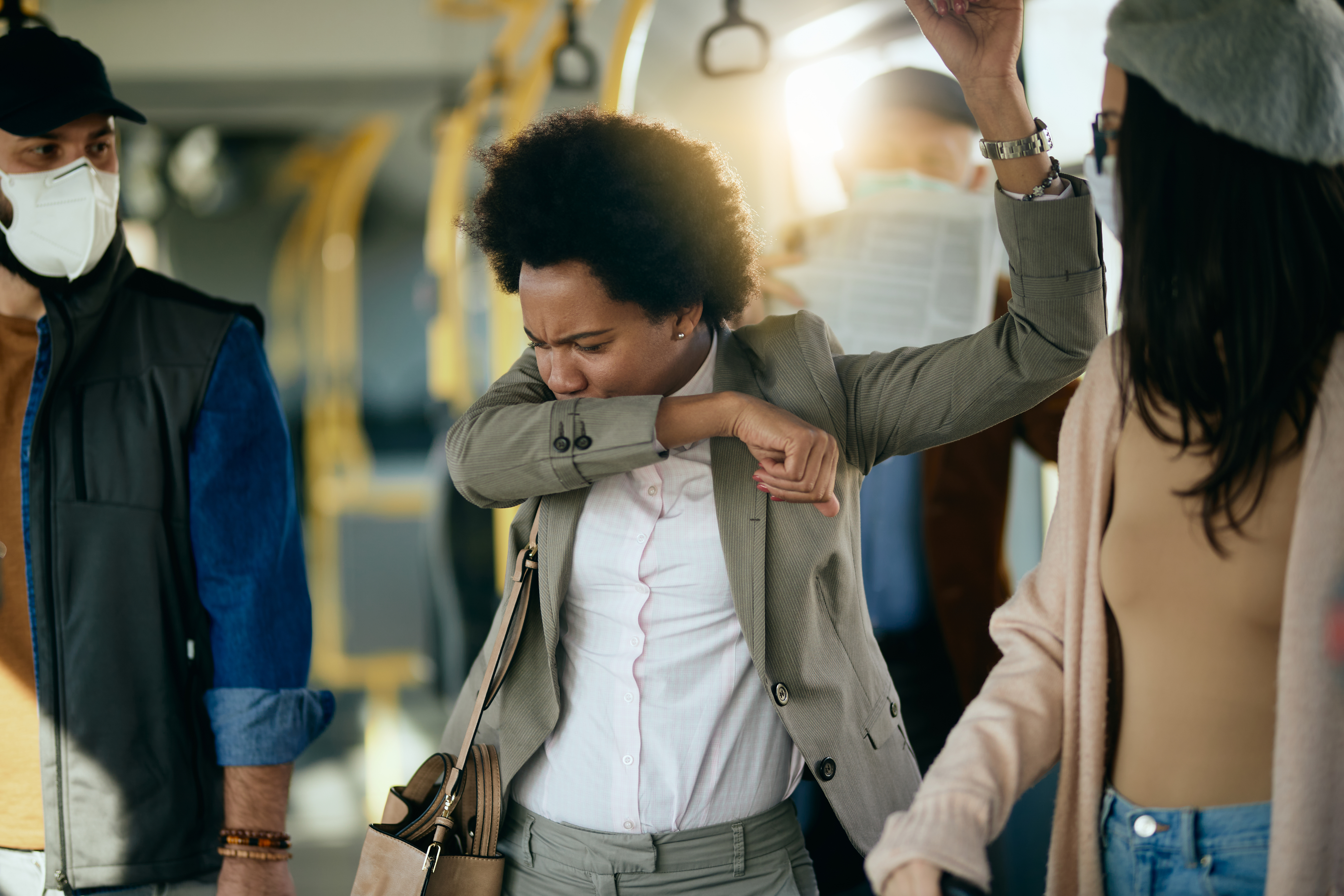 Businesswoman sneezing into elbow while commuting to work by bus