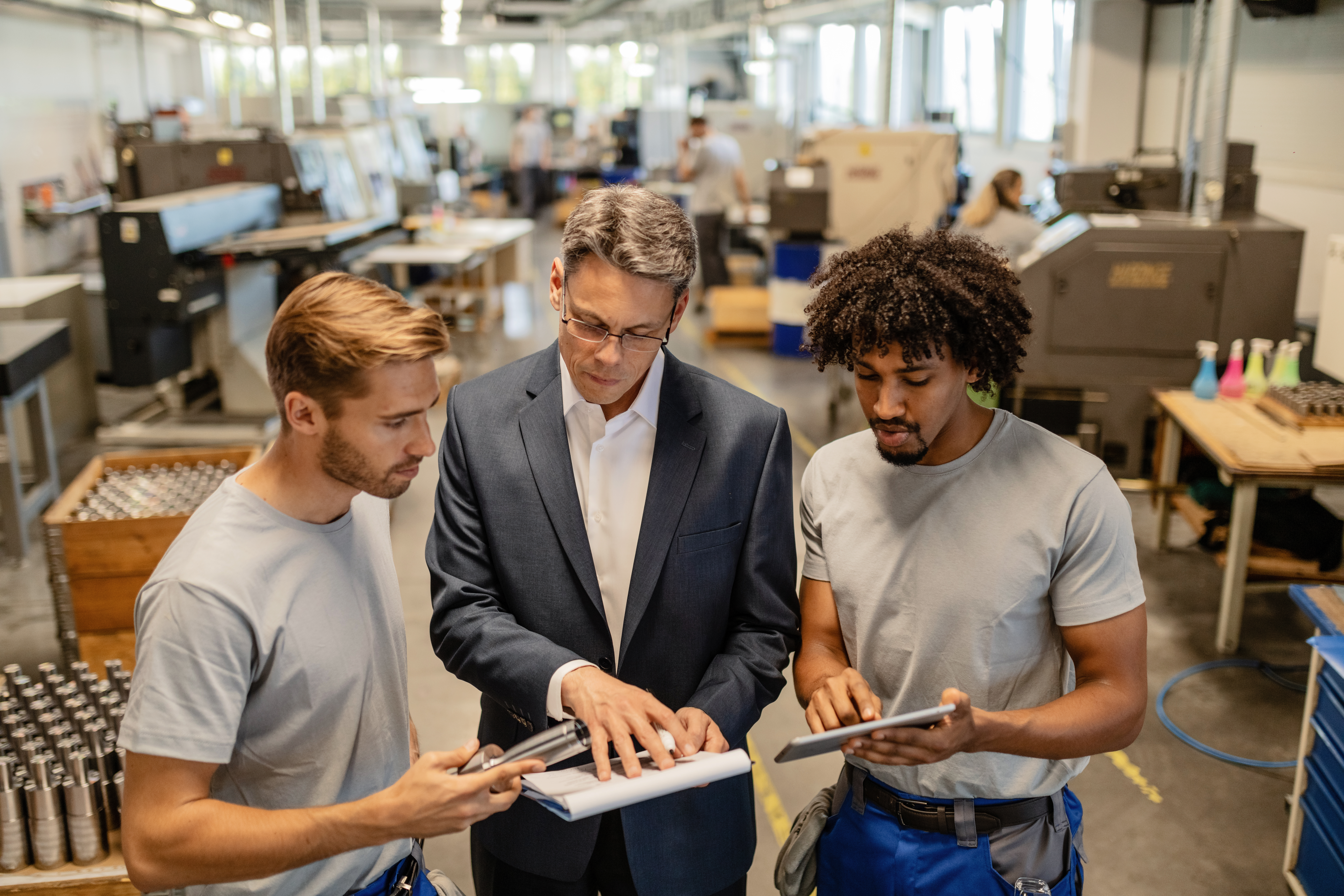 Mid adult engineer and two steel workers going through quality reports while working